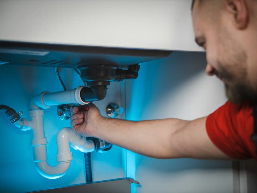 Plumber fixing pipes under a sink